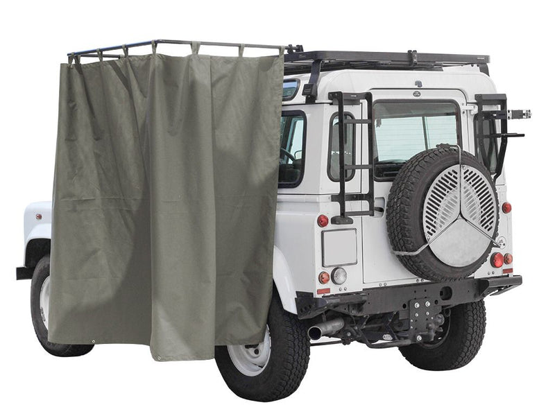 Load image into Gallery viewer, Rear view of a white off-road vehicle equipped with a Front Runner rack mounted shower cubicle with grey privacy curtains.
