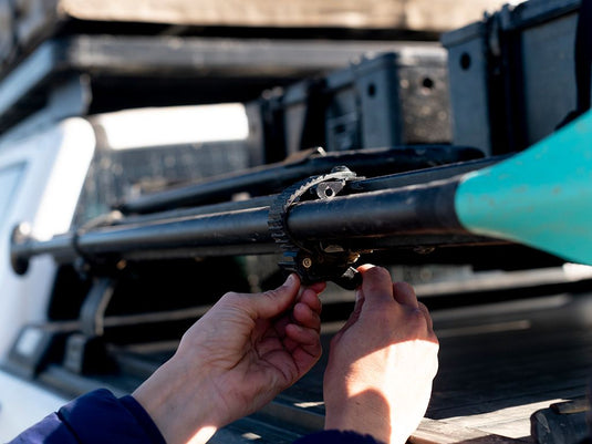 Installation of a Front Runner Ratcheting Spade/Shovel Mount on a vehicle's roof rack.