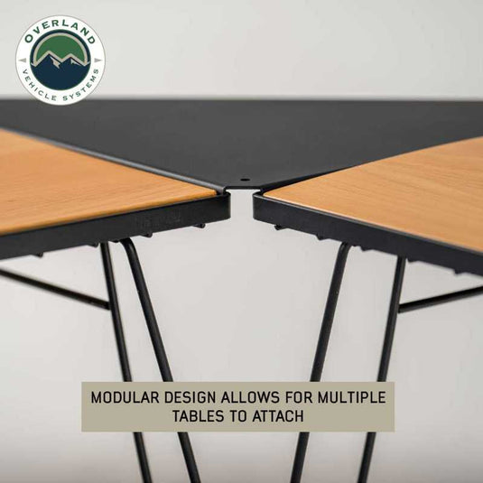 "Overland Vehicle Systems modular camp table with wood base and connecting feature for outdoor setup."