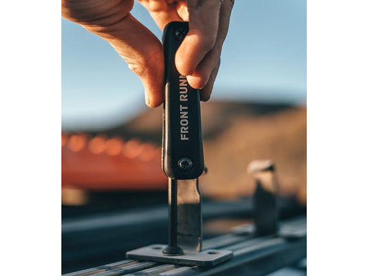 Person using a Front Runner Multi Tool Kit for vehicle maintenance at sunset