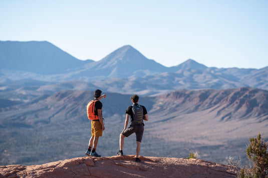 Two hikers with Klymit Echo 12L Hydration Packs overlooking mountainous terrain.