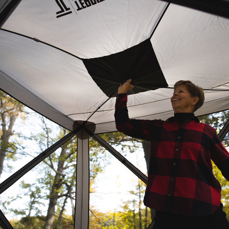 Load image into Gallery viewer, Person in a red and black checked shirt setting up a Territory Tents 4-Sided Portable Screen Tent outdoors.
