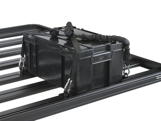 Alt text: "Black Front Runner Adjustable Rack Cargo Chocks securing a storage box on vehicle roof rack."