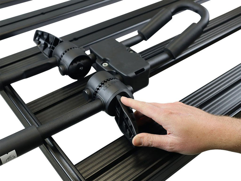 Load image into Gallery viewer, Foldable J-Style Kayak Carrier by Front Runner being installed on roof rack, sturdy black construction with hand adjusting equipment
