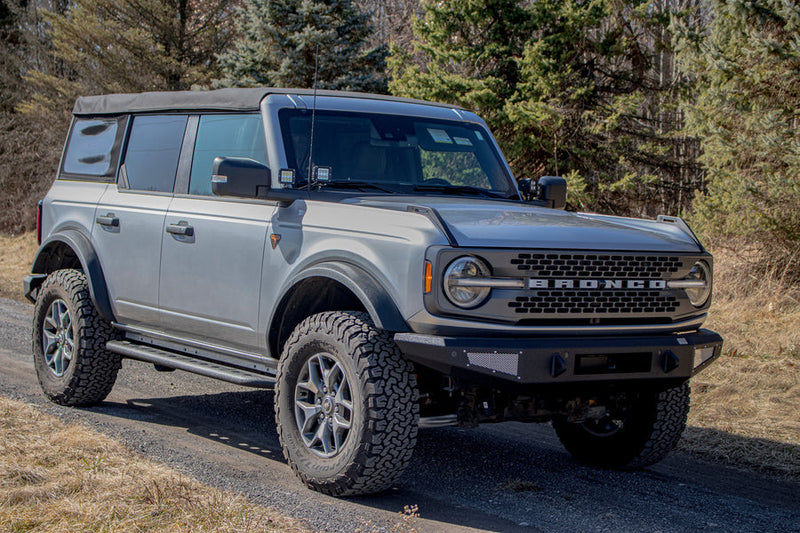 Load image into Gallery viewer, Silver Ford Bronco with Fishbone Offroad Step Sliders installed, showing side profile view on a gravel road.
