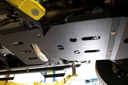 Alt text: "Fishbone Offroad skid plates installed on a 2016-current Toyota Tacoma undercarriage for enhanced protection"