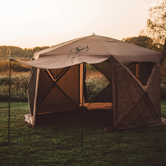 Gazelle Tents G6 Deluxe 6-Sided Portable Gazebo set up in outdoor grassy field at dusk