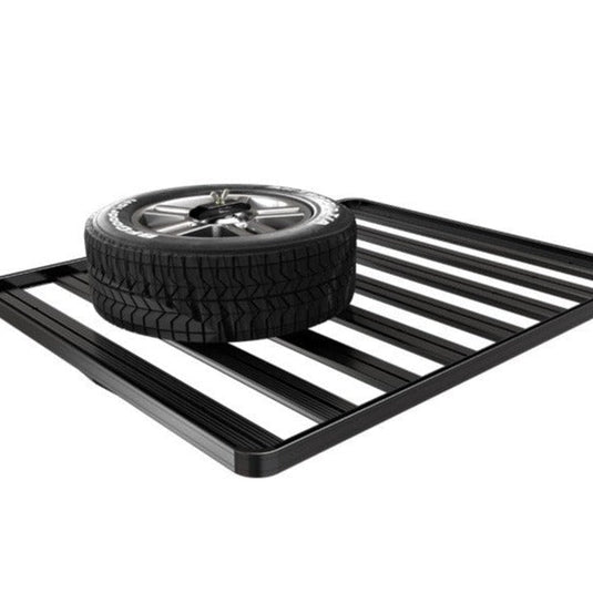 Black Front Runner spare wheel clamp securely holding a vehicle tire on a flat rack for storage and easy access