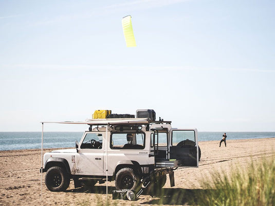 Front Runner Easy-Out Awning 1.4M mounted on off-road vehicle parked on beach