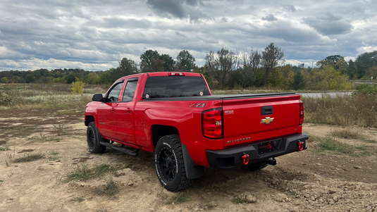 Red Chevrolet Silverado Double Cab with Fishbone Offroad 5-Inch Oval Side Steps installed, parked outdoors.