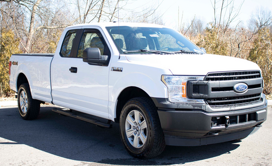 Alt text: "White 2009-2014 Ford F-150 SuperCrew Cab with 5-inch oval side steps by Fishbone Offroad parked outdoors"