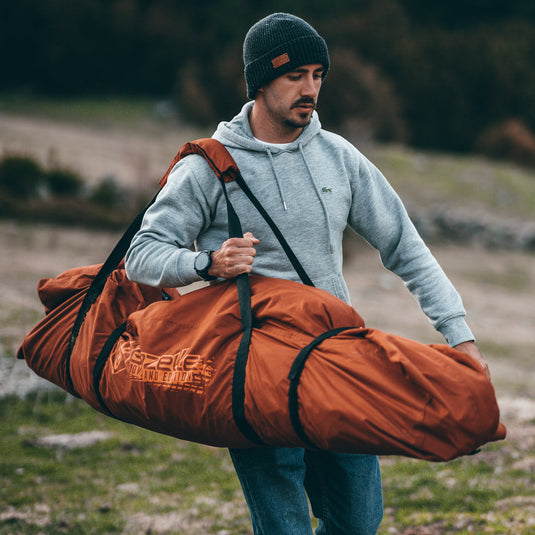 Man carrying Gazelle Tents T4 orange water-resistant duffle bag outdoors