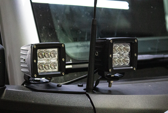 Alt text: "Fishbone Offroad 2022-Current Ford Bronco Cowl Pod Light Bracket Set mounted on vehicle cowl with LED lights visible."