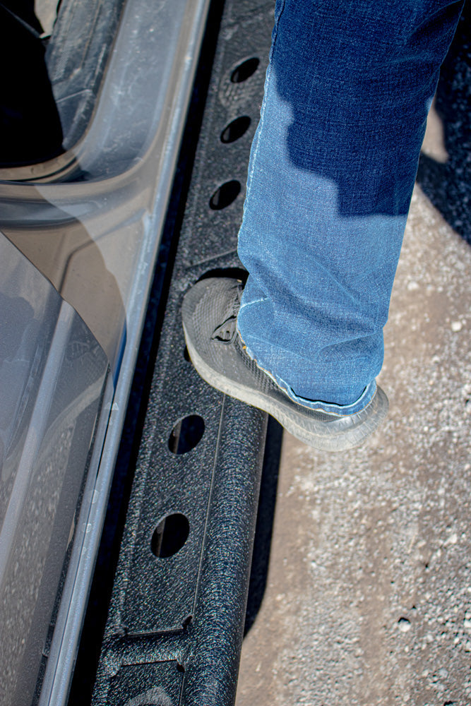 Load image into Gallery viewer, Person stepping on a Fishbone Offroad step slider installed on a 2022 Ford Bronco.
