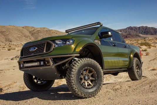 Olive green pickup truck equipped with ICON Vehicle Dynamics Rebound satin black wheels parked in desert terrain