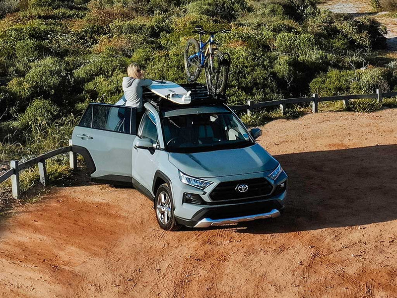 Load image into Gallery viewer, Front Runner Toyota RAV4 with Slimline II Roof Rack Kit installed, featuring mounted bicycles and outdoor adventure gear, ready for off-road travel.
