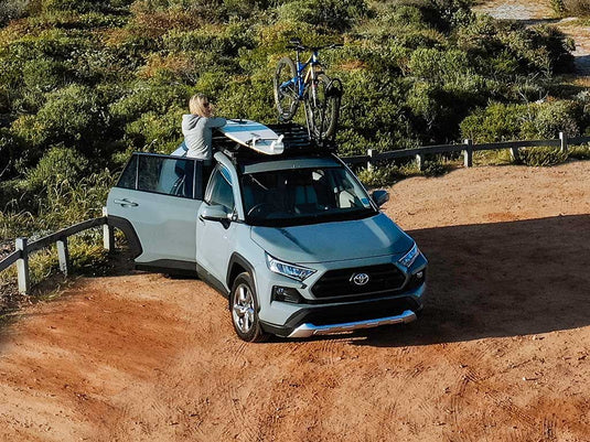 Front Runner Toyota RAV4 with Slimline II Roof Rack Kit installed, featuring mounted bicycles and outdoor adventure gear, ready for off-road travel.