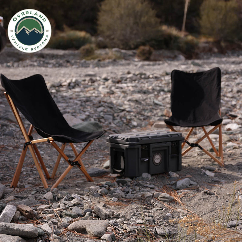 Load image into Gallery viewer, Alt text: &quot;Overland Vehicle Systems Kick It Camp Chairs with wood base set up on a rocky terrain outdoors next to a storage bag.&quot;
