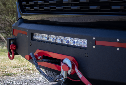 Alt text: "Fishbone Offroad 2019-2023 Ram 1500 Pike Winch Plate installed on truck with LED light bar and red tow hook."