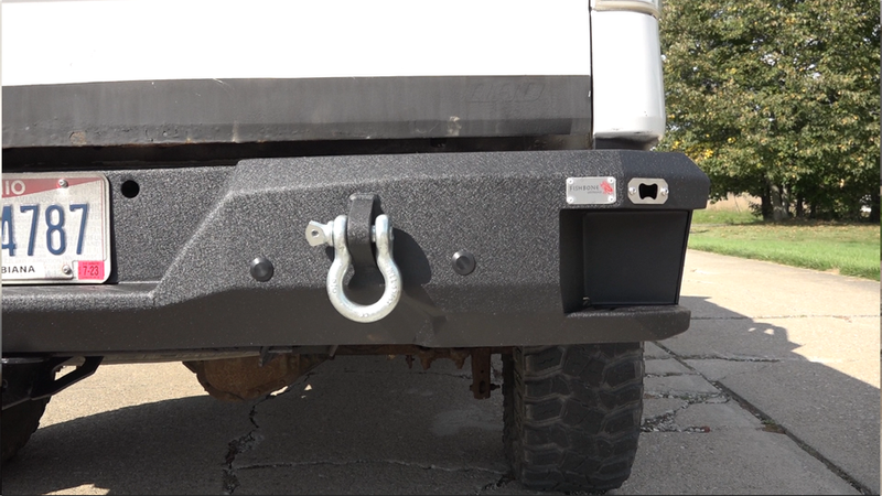 Load image into Gallery viewer, Alt text: &quot;Fishbone Offroad rear step bumper for 2009-2014 Ford F-150 with tow hook and license plate, installed on vehicle.&quot;
