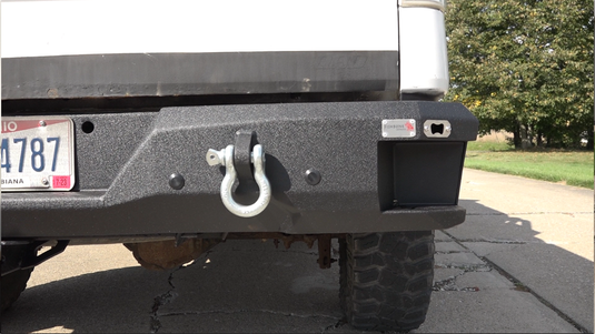 Alt text: "Fishbone Offroad rear step bumper for 2009-2014 Ford F-150 with tow hook and license plate, installed on vehicle."