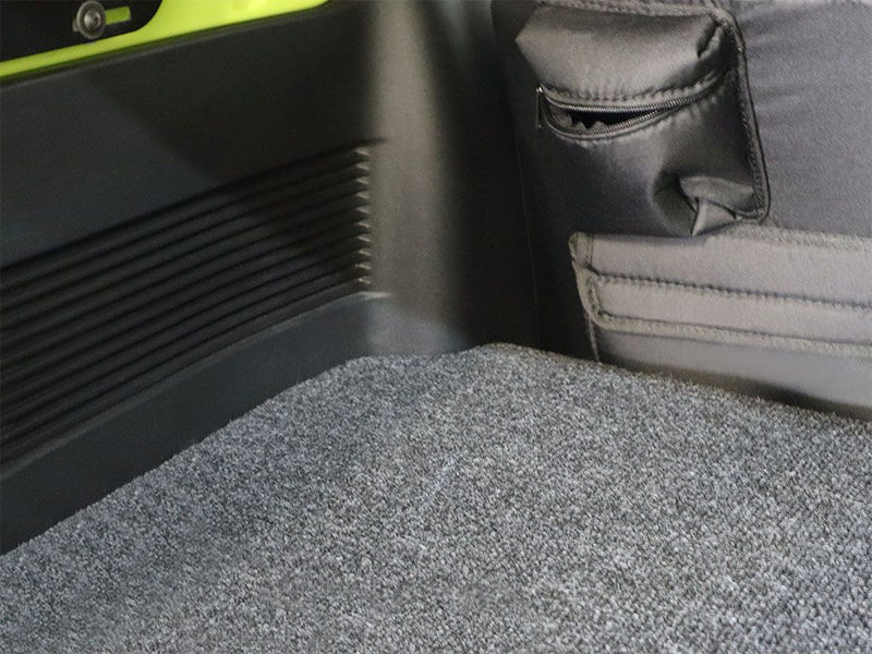 Load image into Gallery viewer, Detailed close-up of the Front Runner Toyota Sequoia 2023 current model Base Deck flooring with textured carpeting and side panel storage pockets.
