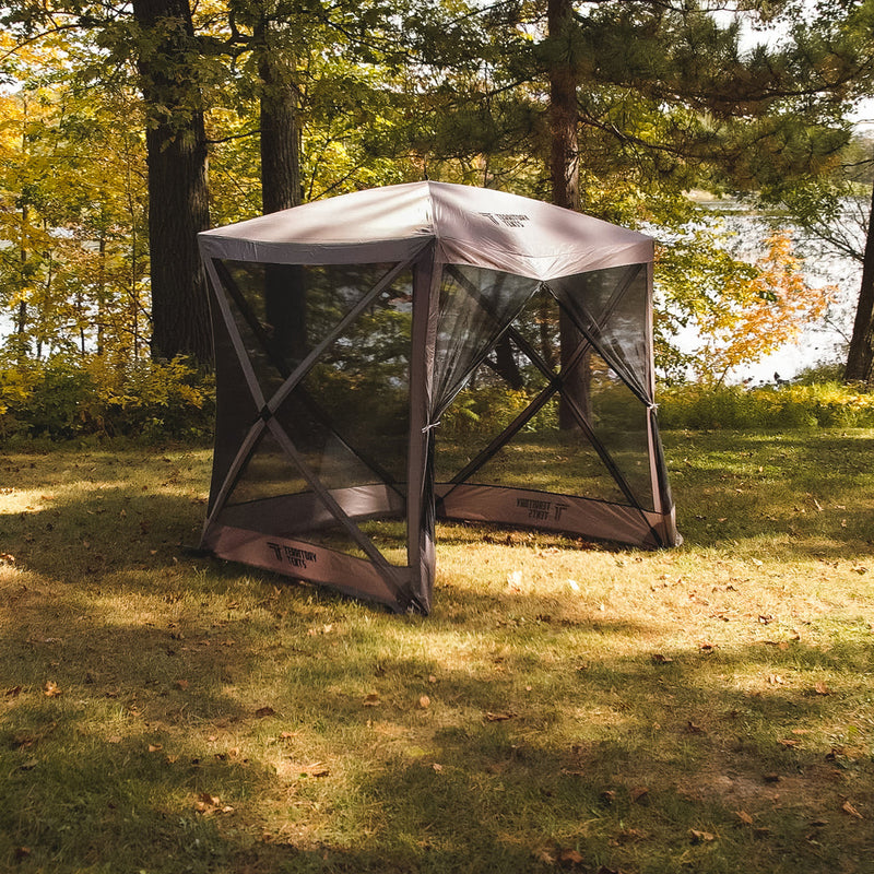 Load image into Gallery viewer, Alt text: &quot;Territory Tents 4-Sided Portable Screen Tent set up on a grassy area with trees and a lake in the background, ideal for outdoor activities and camping.&quot;
