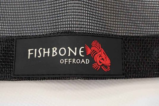 Alt text: "Close-up of Fishbone Offroad logo on a black mesh Jeep Wrangler JLU Full Sun Shade for 2018-current models."