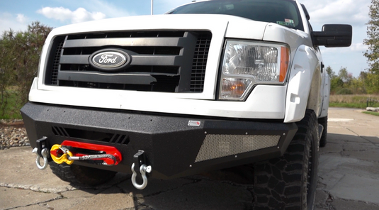 Alt text: "Fishbone Offroad Pelican Front Bumper on 2009-2014 Ford F-150 with tow hooks and LED light bars"