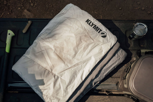 Klymit Horizon Overland Blanket folded on a tailgate with outdoor gear.