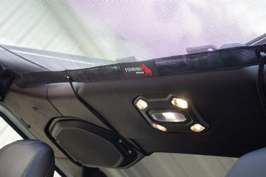 Alt text: "Fishbone Offroad rear sun shade installed in a 2020 Jeep Gladiator JT, showing the mesh screen and interior roof lights."