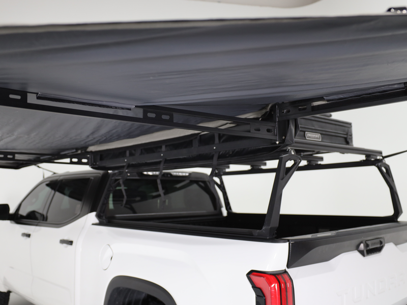 Load image into Gallery viewer, Alt text: &quot;Freespirit Recreation 180 Degree Awning attached to a white pickup truck, showing the extended canopy and sturdy support frame.&quot;
