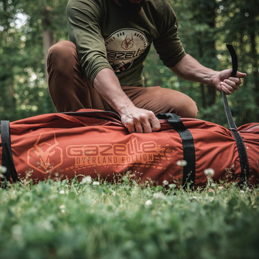 Person unpacking Gazelle Tents T4 Hub Tent Overland Edition in a forest setting