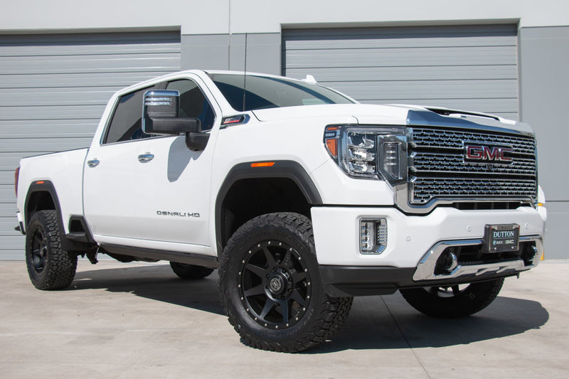 Load image into Gallery viewer, White GMC truck with ICON Vehicle Dynamics Rebound bronze wheels parked outside.

