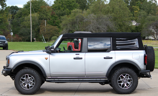 Alt text: "Silver 2022 Ford Bronco equipped with Fishbone Offroad Step Sliders on display outdoors"