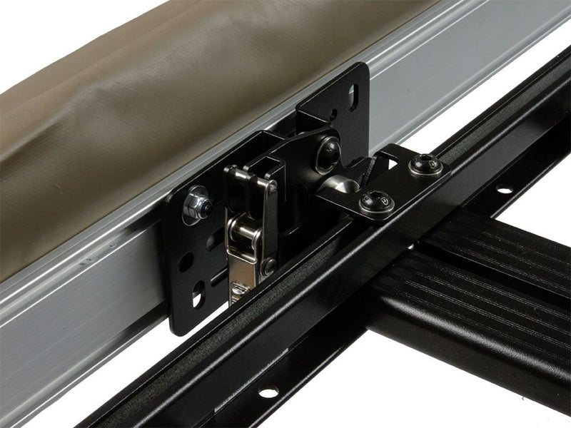 Load image into Gallery viewer, Close-up view of a Front Runner Quick Release Awning Mount Kit installed on a vehicle rack, showcasing the sturdy black metal bracket and bolts for easy attachment and release.
