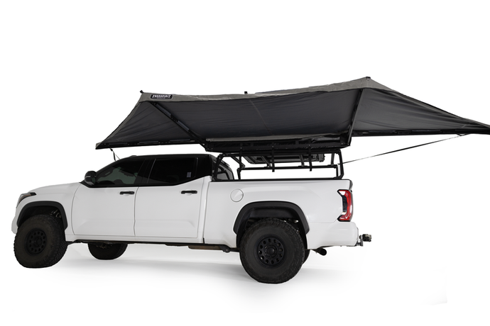 Alt text: inchWhite pickup truck equipped with Freespirit Recreation 180 Degree Awning attached to the roof rack, fully extended to provide shade.inch