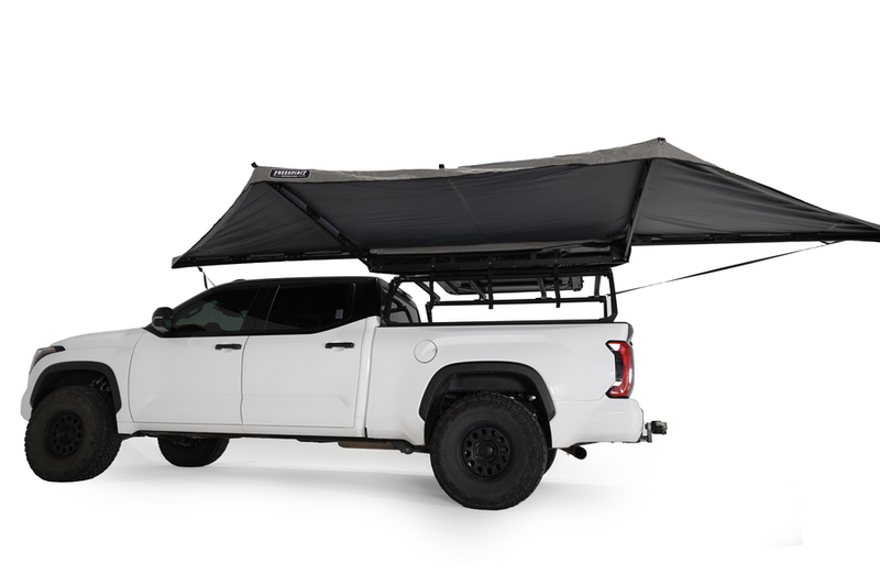 Load image into Gallery viewer, Alt text: &quot;White pickup truck equipped with Freespirit Recreation 180 Degree Awning attached to the roof rack, fully extended to provide shade.&quot;
