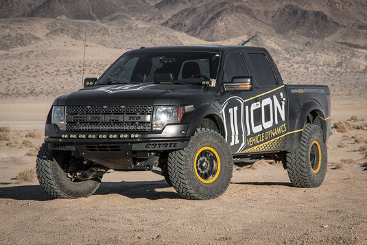 Black pickup truck with ICON Vehicle Dynamics branding and bronze six-speed wheels in desert terrain.
