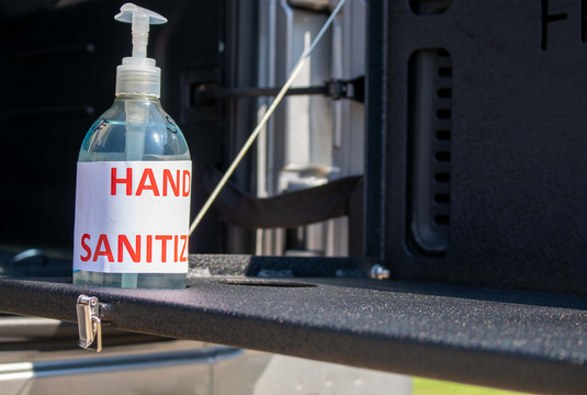 Alt text: "Hand sanitizer bottle on Fishbone Offroad tailgate table installed in JK, JKU, JL, JLU Wrangler or 2021 Ford Bronco, demonstrating table utility."