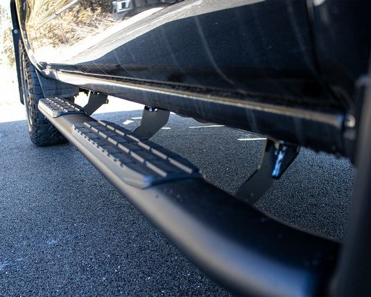 Alt text: "Close-up of 5 inch oval side steps by Fishbone Offroad on a Chevy/GMC 1500, 2500, 3500 crew cab with anti-slip tread pattern."