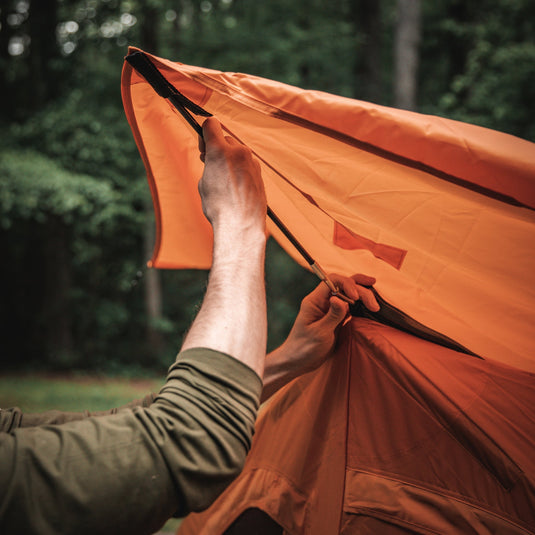 Person setting up a Gazelle Tents T4 Hub Tent Overland Edition in the forest