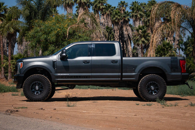 Load image into Gallery viewer, Pickup truck equipped with ICON Vehicle Dynamics Rebound HD wheels in satin black finish parked outdoors surrounded by palm trees.

