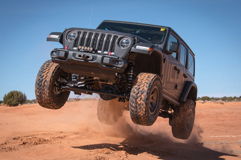 Load image into Gallery viewer, Jeep equipped with ICON Vehicle Dynamics rebound wheels in bronze catching air off-road
