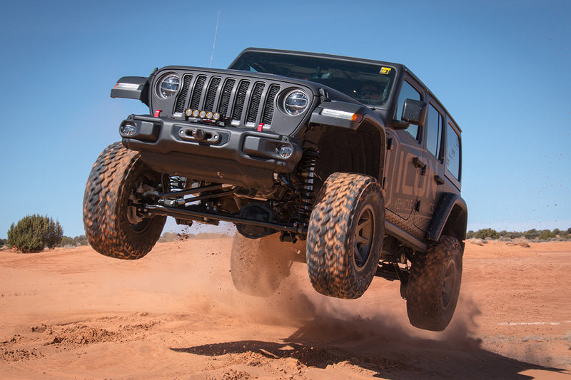 Load image into Gallery viewer, Jeep equipped with ICON Vehicle Dynamics Rebound satin black wheels performing an off-road jump in a desert setting
