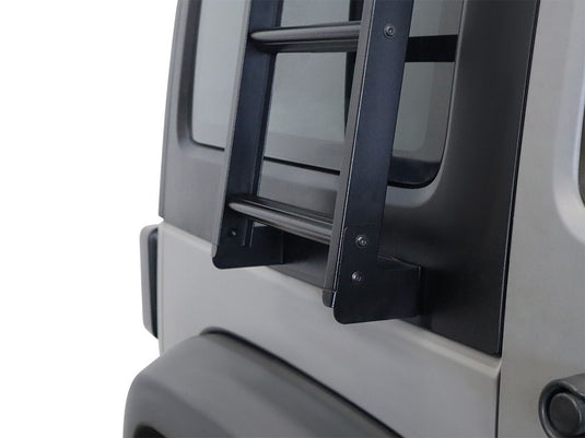Alt text: "Close-up of the Front Runner Jeep Wrangler JK Side Mount Ladder attached to the rear door of the vehicle, showcasing the sturdy black metal construction and secure mounting system."
