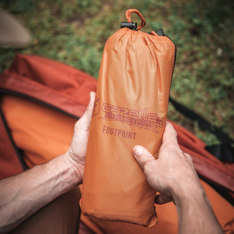 Load image into Gallery viewer, Gazelle Tents T4 Hub Tent Overland Edition footprint package held in hands with camping equipment in the background
