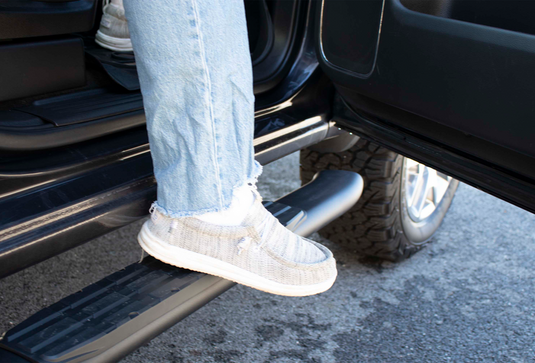 Alt text: "Close-up of Fishbone Offroad 5 inch oval side steps on Chevy/GMC 1500, 2500, 3500 Double Cab with person stepping on it, showcasing convenience and durability."