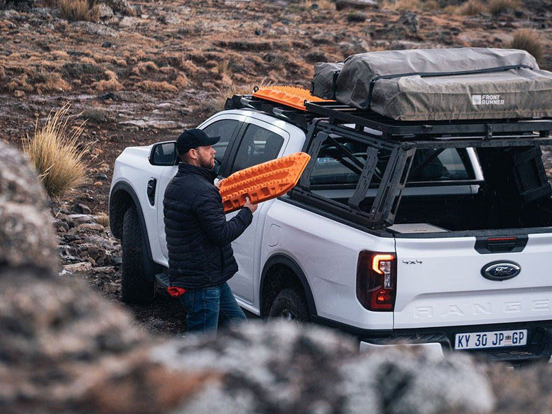 Load image into Gallery viewer, Man installing Front Runner Pro Bed Universal Accessory Mount on pickup truck.
