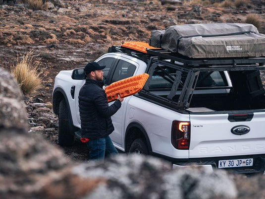 Man installing Front Runner Pro Bed Universal Accessory Mount on pickup truck.